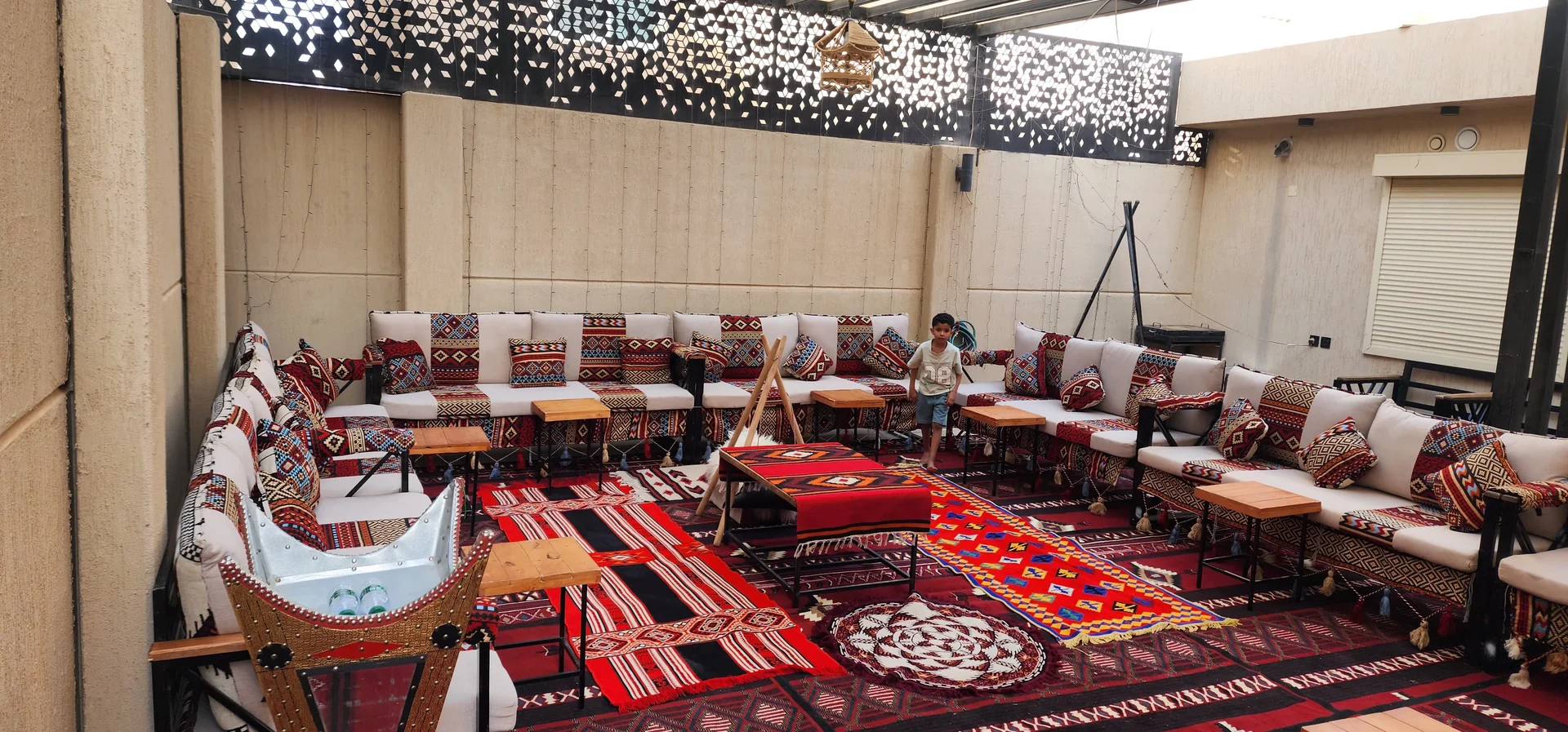 جلسة كنب تراثية واسعة حول سجاد أحمر وطاولات ضيافة داخل قاعة مزخرفة.